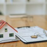 House model, keys and contract document on wooden table