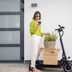 a girl with a phone holding stands near an electric scooter