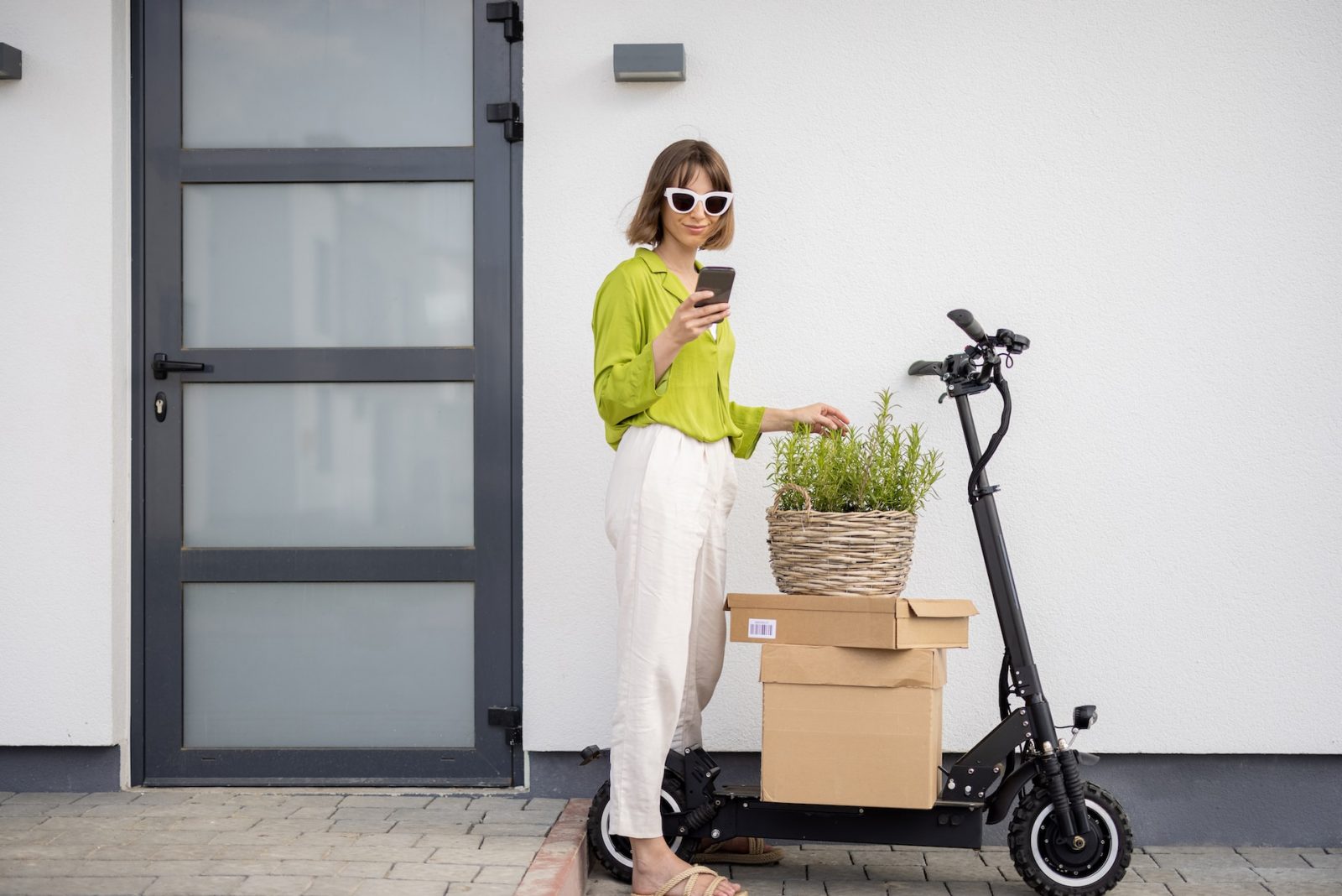 a girl with a phone holding stands near an electric scooter